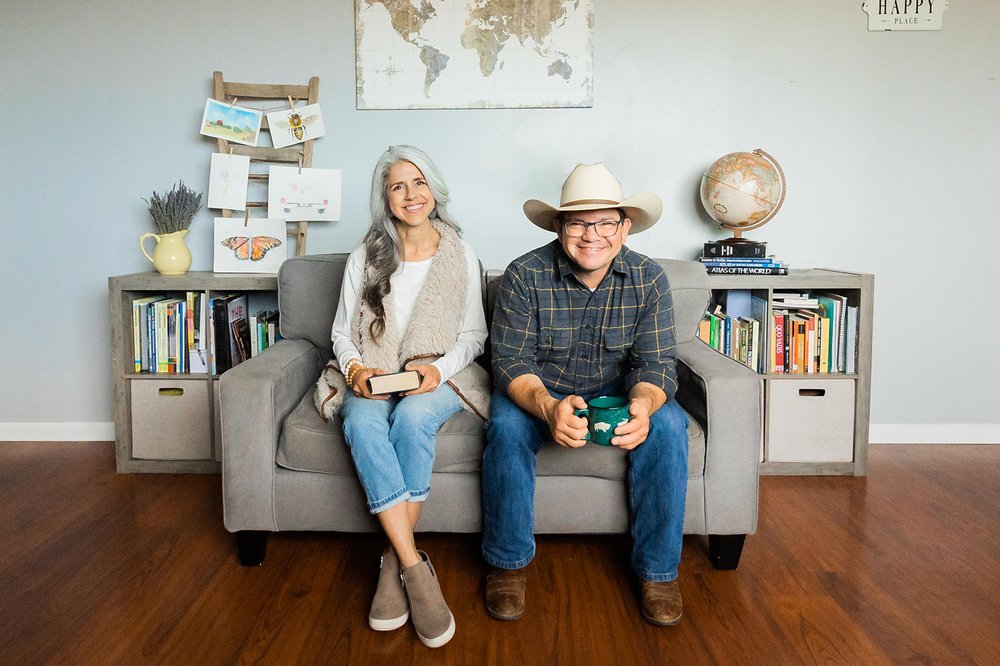Mike and Linda sitting together at home, bookshelves and a globe behind them